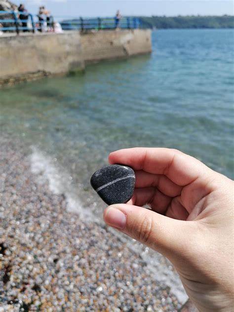 Person holding a striped wishing stone by the ocean